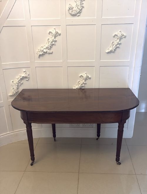 A long Regency extending dining table crafted from polished figured mahogany with reeded legs set on brass castors. View XV