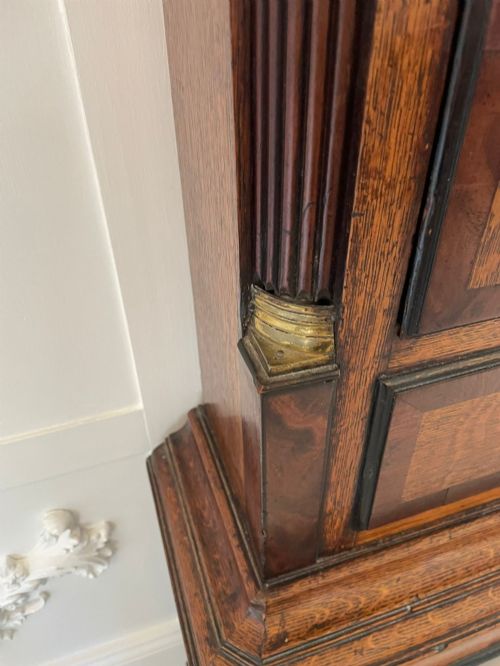 fig 2. An antique George III oak and mahogany longcase clock with a swan-neck pediment, reeded columns, and a painted moon phase dial.