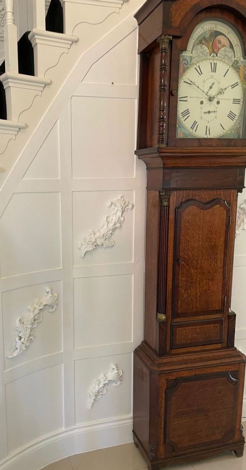 fig 3. An antique George III oak and mahogany longcase clock with a swan-neck pediment, reeded columns, and a painted moon phase dial.