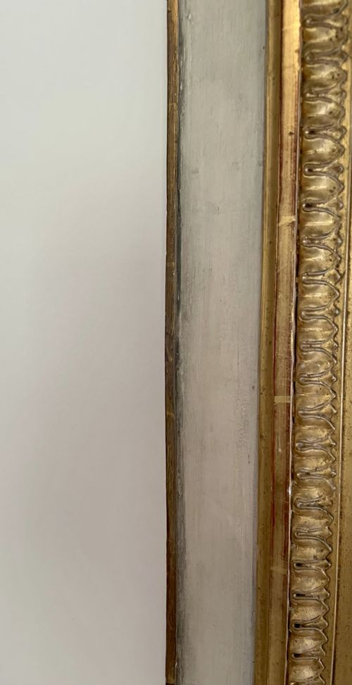 A tall rectangular Victorian mirror featuring a white painted outer frame, gilded beaded inner border, and a gilded ribbon crest with floral swags. View III