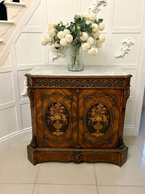 fig 1. A French Louis XVI style wooden side cabinet featuring a white marble top, gilt-bronze mounts, and two door panels decorated with floral marquetry.