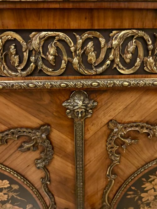 fig 2. A French Louis XVI style wooden side cabinet featuring a white marble top, gilt-bronze mounts, and two door panels decorated with floral marquetry.