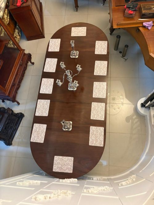 fig 1. A large mahogany extending dining table featuring an oval surface with two additional leaves, supported by splayed pedestal legs with brass castors.