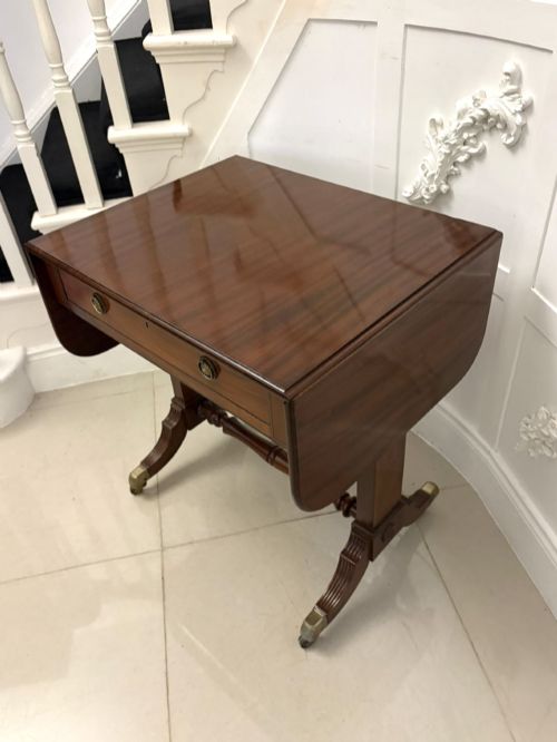 fig 3. A Regency period mahogany sofa table featuring two drop-leaf sides, a single drawer with brass ring handles, reeded splayed legs, a turned stretcher bar, and brass castors.