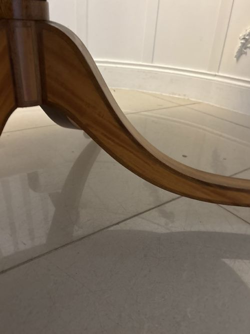 fig 2. An antique Regency style oval mahogany tilt-top dining table featuring a figured timber top with satinwood crossbanding mounted on a pedestal base with brass castors.