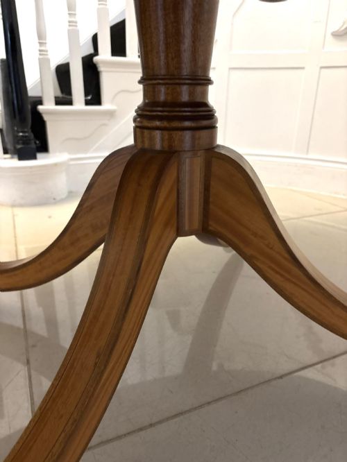 fig 3. An antique Regency style oval mahogany tilt-top dining table featuring a figured timber top with satinwood crossbanding mounted on a pedestal base with brass castors.