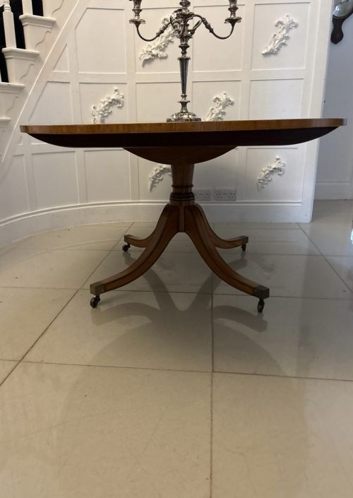 fig 4. An antique Regency style oval mahogany tilt-top dining table featuring a figured timber top with satinwood crossbanding mounted on a pedestal base with brass castors.