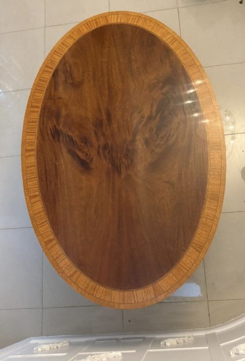 An antique Regency style oval mahogany tilt-top dining table featuring a figured timber top with satinwood crossbanding mounted on a pedestal base with brass castors. View XIV