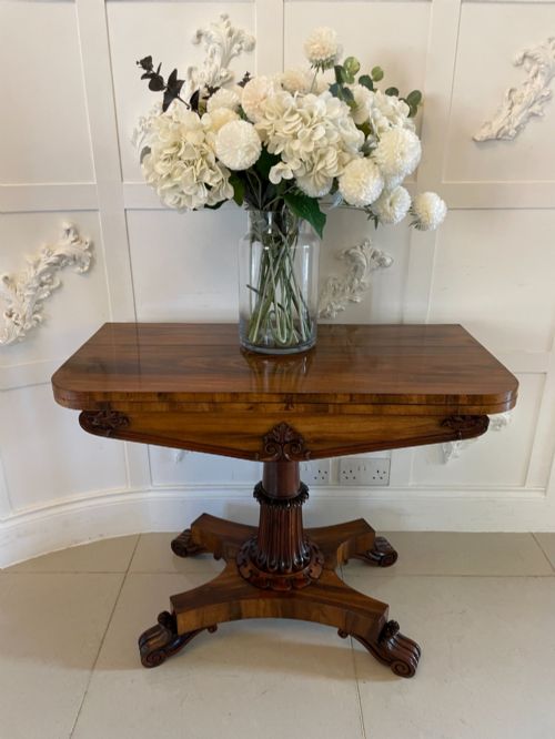 fig 1. An antique Victorian rosewood fold-over card table featuring a carved frieze, a fluted pedestal column, and a quadform base with scroll feet.