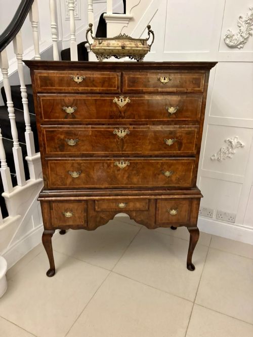 fig 1. An early eighteenth-century George I walnut chest on stand featuring crossbanded drawers, brass drop handles, and cabriole legs with pad feet.