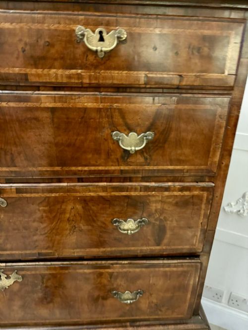 fig 2. An early eighteenth-century George I walnut chest on stand featuring crossbanded drawers, brass drop handles, and cabriole legs with pad feet.