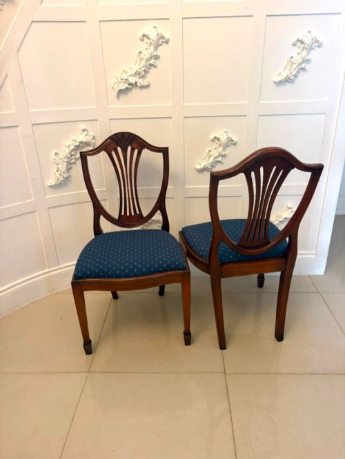 fig 2. A set of twelve mahogany shield back dining chairs featuring carved backrest splats, square tapered legs, and blue patterned upholstered seats.