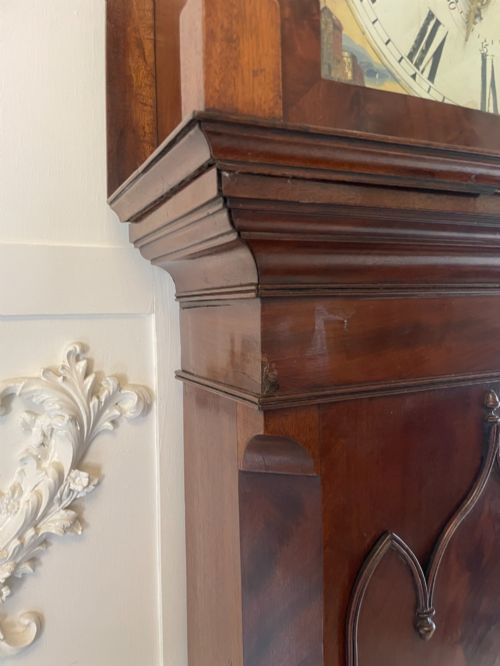 fig 1. A George III flame mahogany longcase clock featuring a swan-neck pediment, turned hood columns, a painted arch dial, and a gothic-arched trunk door.