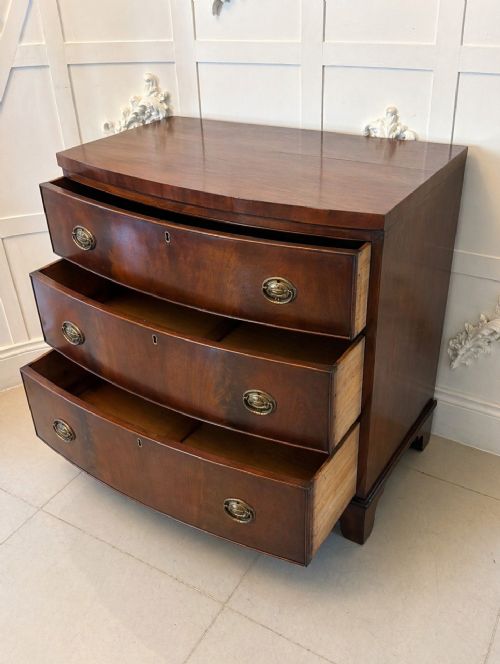 fig 1. A Georgian mahogany bow-front chest of three drawers featuring oval brass drop handles and raised on bracket feet.