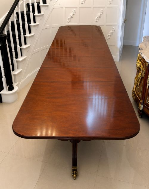 fig 1. A long extendable mahogany banquet dining table set on four turned pedestal bases with splayed legs and brass castors.