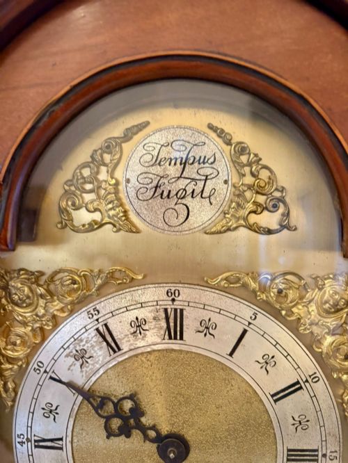 fig 4. An Edwardian mahogany longcase clock with satinwood urn inlay on the door and a brass dial with Tempus Fugit inscription.