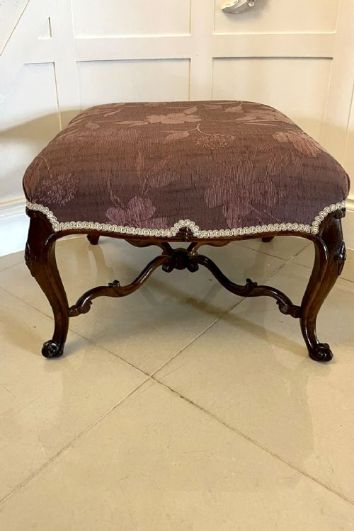 An antique Victorian stool featuring carved dark rosewood cabriole legs and a low rectangular padded seat upholstered in a floral pattern fabric. View VII