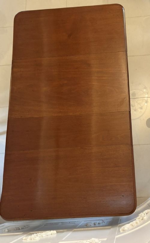 A large Victorian extending mahogany dining table featuring rounded corners, turned legs, brass castors, and a polished dark wood surface. View IX