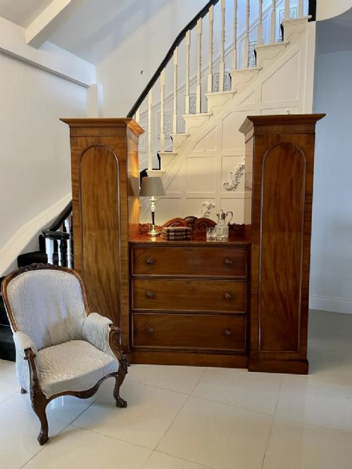 A William IV mahogany breakfront wardrobe featuring two tall outer cupboards flanking a central chest of three drawers with a carved gallery back. View II