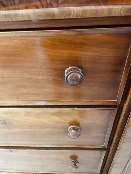 A William IV mahogany breakfront wardrobe featuring two tall outer cupboards flanking a central chest of three drawers with a carved gallery back. View IX