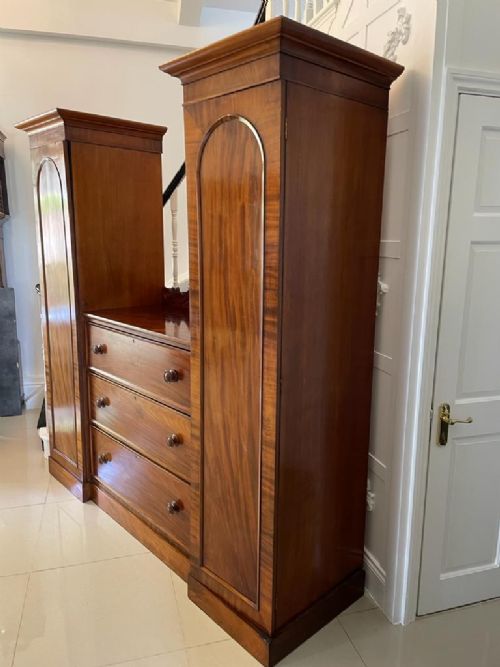 A William IV mahogany breakfront wardrobe featuring two tall outer cupboards flanking a central chest of three drawers with a carved gallery back. View XIV