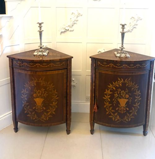 fig 5. A pair of Victorian mahogany corner cabinets featuring curved bow fronts with floral urn marquetry inlays and tapered square feet.