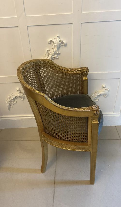 A pair of French Louis XVI style carved giltwood tub armchairs featuring curved caned backs and dark blue velvet seat cushions. View XI