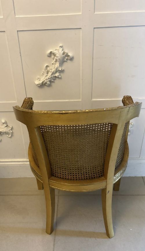A pair of French Louis XVI style carved giltwood tub armchairs featuring curved caned backs and dark blue velvet seat cushions. View XII