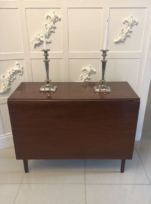 fig 3. An antique Georgian mahogany drop-leaf dining table shown folded closed with square straight legs and a polished dark wood surface.