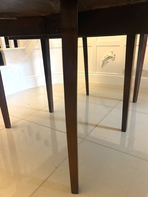 fig 4. An antique Georgian mahogany drop-leaf dining table shown folded closed with square straight legs and a polished dark wood surface.
