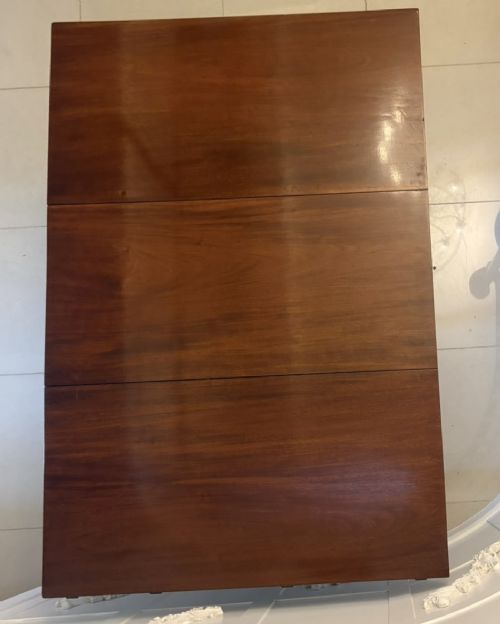 fig 5. An antique Georgian mahogany drop-leaf dining table shown folded closed with square straight legs and a polished dark wood surface.