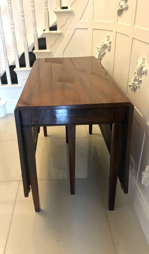 An antique Georgian mahogany drop-leaf dining table shown folded closed with square straight legs and a polished dark wood surface. View IX