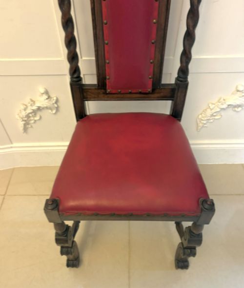 fig 2. A set of high-backed dark oak dining chairs with barley twist uprights, carved cresting rails, and red upholstered seats and back panels with stud trim.