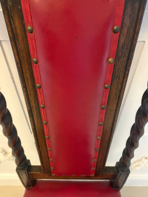 fig 3. A set of high-backed dark oak dining chairs with barley twist uprights, carved cresting rails, and red upholstered seats and back panels with stud trim.