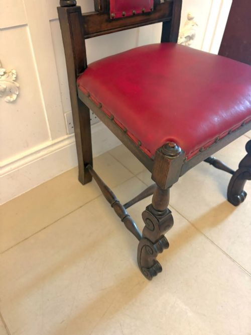 fig 4. A set of high-backed dark oak dining chairs with barley twist uprights, carved cresting rails, and red upholstered seats and back panels with stud trim.