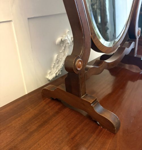 fig 3. An Edwardian mahogany toilet mirror featuring a shield-shaped frame with bevelled glass mounted on a swivelling stand with brass knobs.