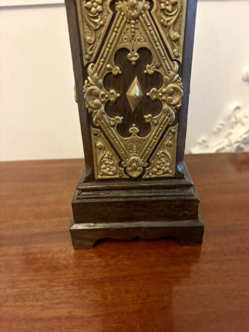 fig 9. A dark oak miniature grandfather table clock with ornate embossed brass panels and a white dial featuring Roman numerals.