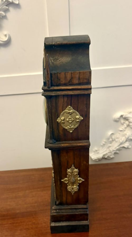 fig 10. A dark oak miniature grandfather table clock with ornate embossed brass panels and a white dial featuring Roman numerals.