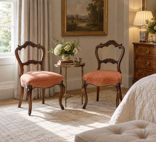 fig 2. A pair of Victorian carved walnut side chairs featuring open balloon backs with foliate carvings, cabriole legs, and terracotta patterned fabric upholstered seats.