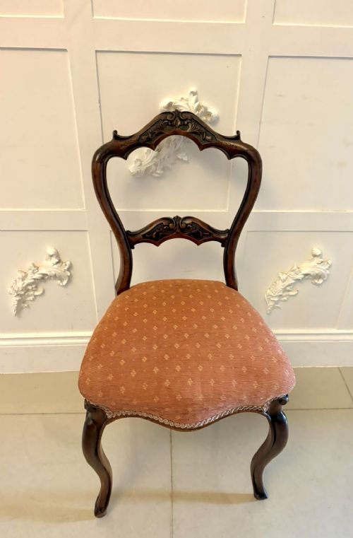 A pair of Victorian carved walnut side chairs featuring open balloon backs with foliate carvings, cabriole legs, and terracotta patterned fabric upholstered seats. View XV