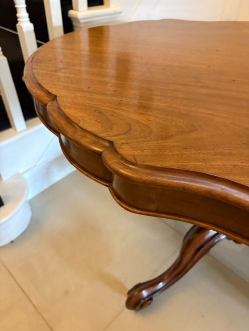 fig 3. A Victorian figured mahogany tilt-top centre table featuring a shaped serpentine top positioned vertically on a carved central pedestal with four splayed legs.