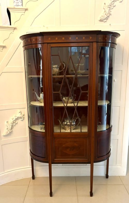 fig 3. An Edwardian mahogany display cabinet featuring bow-ended glass sides, a central astragal glazed door, and satinwood marquetry inlay.
