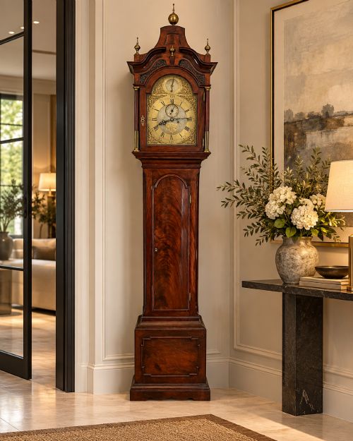fig 1. An antique Georgian longcase grandfather clock crafted from flame mahogany wood with an arched brass dial and brass finials.