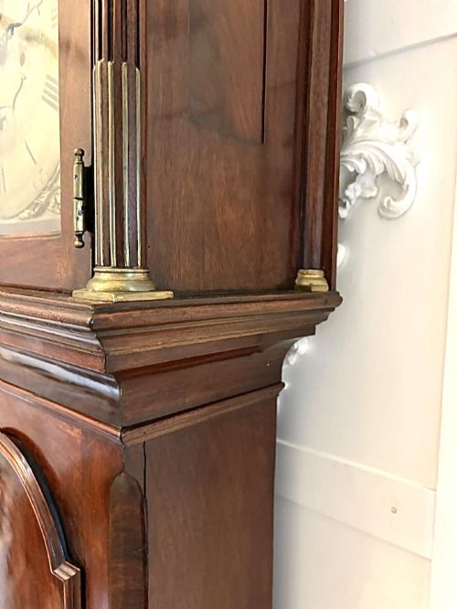fig 4. An antique Georgian longcase grandfather clock crafted from flame mahogany wood with an arched brass dial and brass finials.