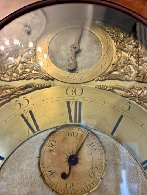 fig 8. An antique Georgian longcase grandfather clock crafted from flame mahogany wood with an arched brass dial and brass finials.