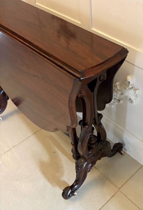An antique Victorian rosewood Sutherland table with drop leaves, carved legs, and brass castors. View XI