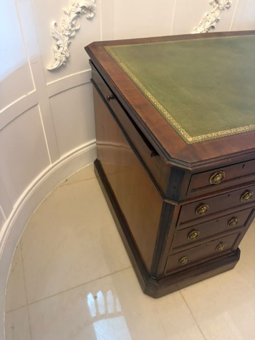 fig 2. A Victorian mahogany pedestal desk featuring a green leather inset writing surface, nine drawers with brass ring pulls, and a plinth base.