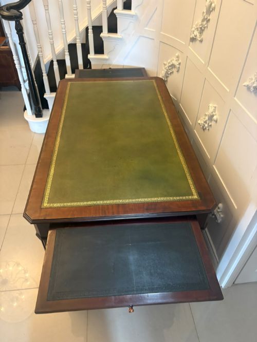 fig 3. A Victorian mahogany pedestal desk featuring a green leather inset writing surface, nine drawers with brass ring pulls, and a plinth base.