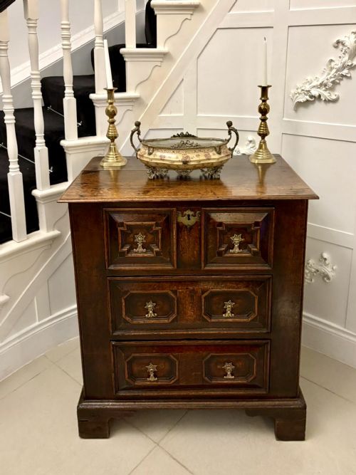 fig 2. A dark oak Jacobean chest of drawers featuring geometric moulded drawer fronts and brass drop handles.