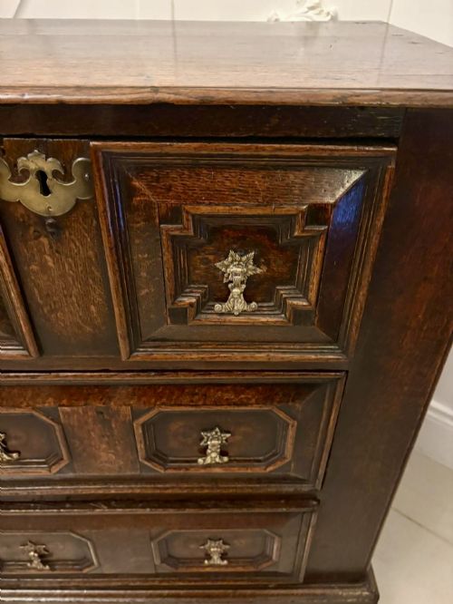 fig 3. A dark oak Jacobean chest of drawers featuring geometric moulded drawer fronts and brass drop handles.